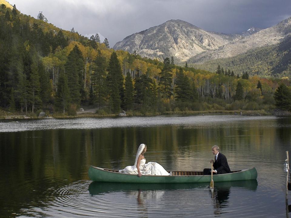 Kevin Costner and Christine Baumgartner in a canoe, wearing their wedding outfits.