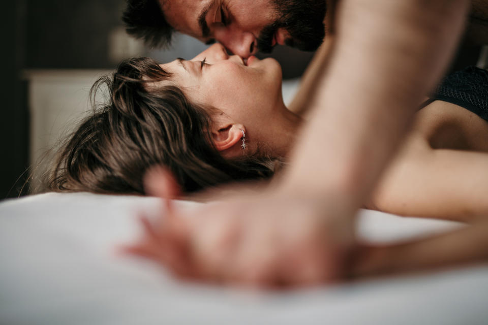 The young couple kissing in the bed and being gentle.