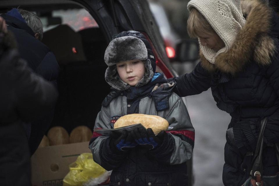 A boy carries a loaf of bread after receiving humanitarian aid in Avdiivka in Avdiivka, Ukraine, Saturday, Feb. 4, 2017. Fighting in eastern Ukraine sharply escalated this week. Ukraine's military said several soldiers were killed over the past day in shelling in eastern Ukraine, where fighting has escalated over the past week. (AP Photo/Evgeniy Maloletka)