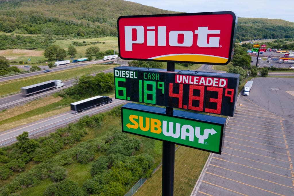 Trucks and cars drive by a Pilot Travel Center sign displaying fuel prices in Bath, New York, on Monday, June 20, 2022. Warren Buffett’s Berkshire Hathaway says the billionaire Haslam family tried to bribe at least 15 executives at the Pilot truck stop chain with millions of dollars to inflate the company’s profits this year because that would force Berkshire to pay more for the Haslams’ remaining 20% stake in the company. (AP Photo/Ted Shaffrey, File)