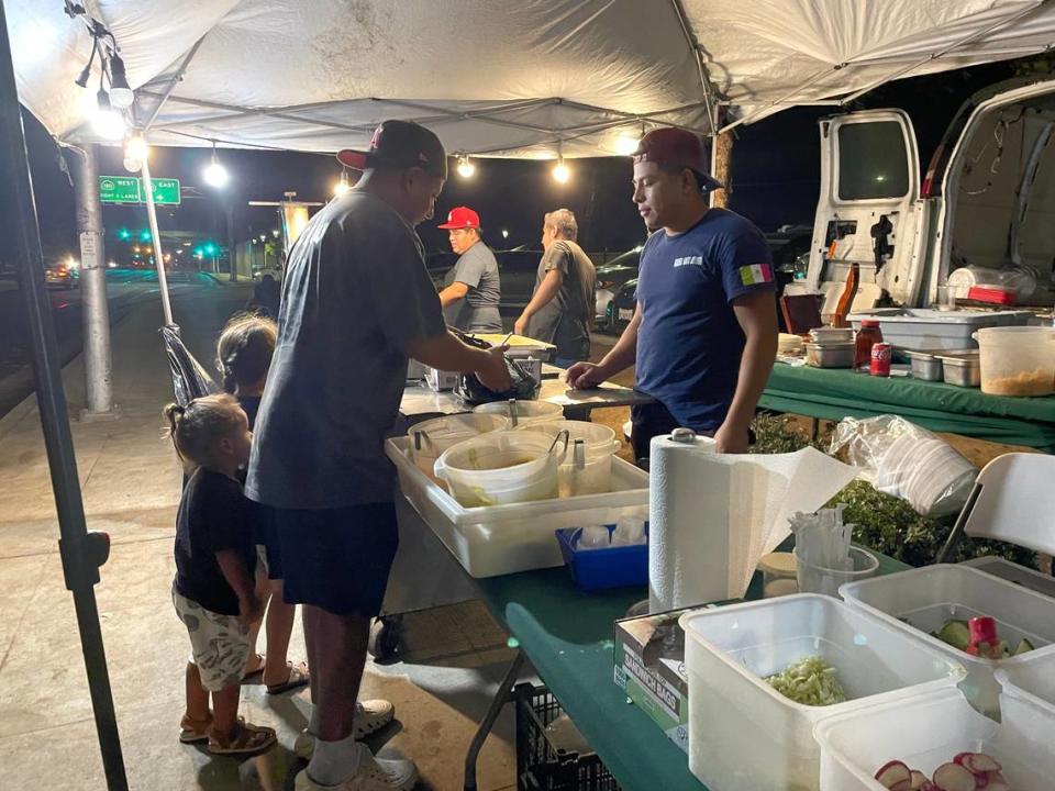 A family picks up their order at Taquería Santo Domingo, on Chestnut Avenue in Fresno, California on August 14, 2023. The city has seen an increase in licensed and unlicensed mobile food businesses in the aftermath of the coronavirus pandemic.