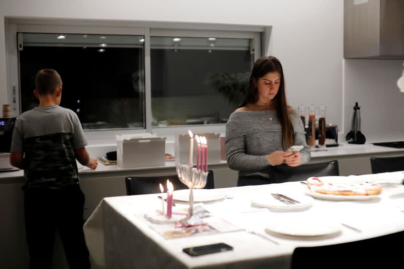 Grandchildren of Israeli Holocaust survivor Avraham Harshalom, stand next to a hanukkiyah, a candlestick with nine branches that is lit to mark Hanukkah, the 8-day Jewish Festival of Lights, in Ramat Gan, Israel
