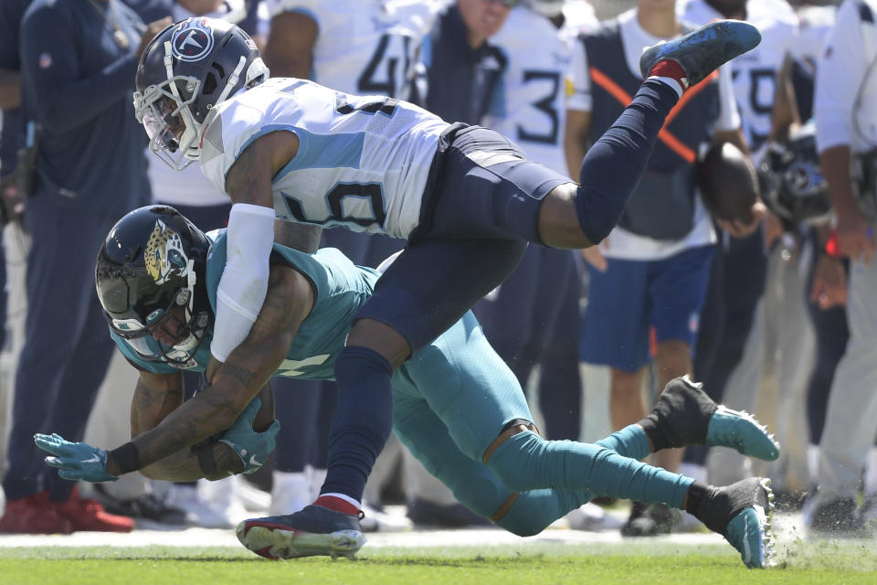 Jacksonville Jaguars wide receiver Marvin Jones, left, is brought down after a reception by Tennessee Titans cornerback Kristian Fulton during the first half of an NFL football game, Sunday, Oct. 10, 2021, in Jacksonville, Fla. (AP Photo/Phelan M. Ebenhack)