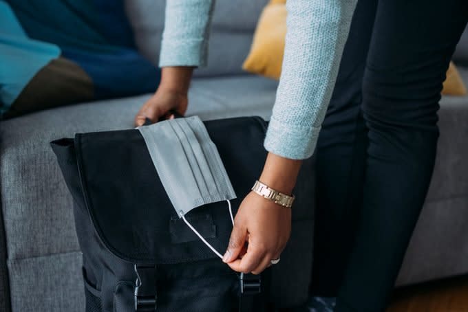 Anonymous Female Packing Stuff in Backpack and Putting Face Mask on the Backpack