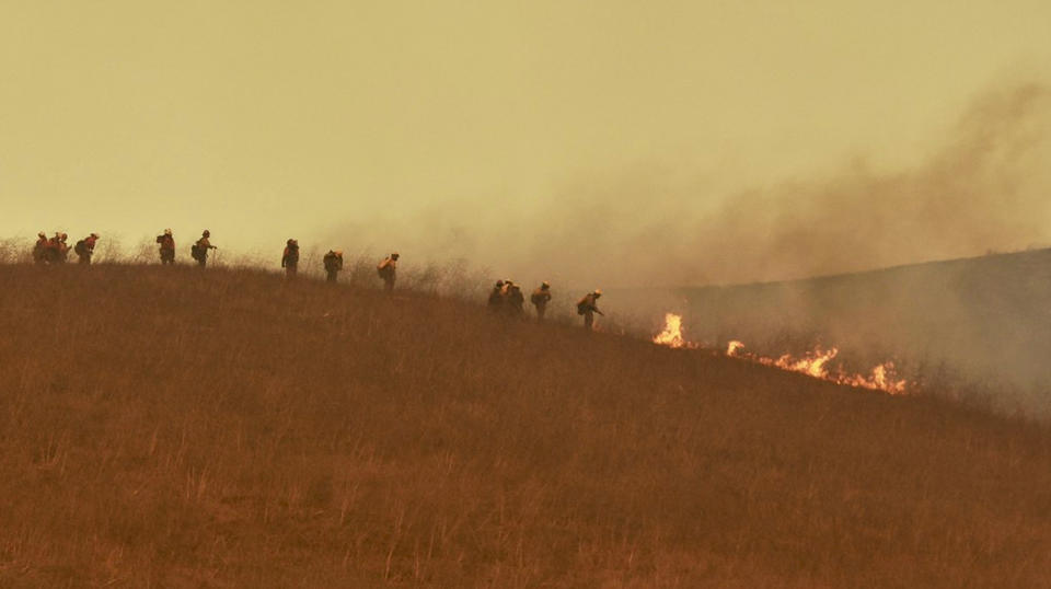 In this photo provided by the Santa Barbara County Fire Department, a hand crew works on a hill to extinguish a fire Tuesday, Oct. 12, 2021, in Goleta, Calif. (Mike Eliason/Santa Barbara County Fire Department via AP)