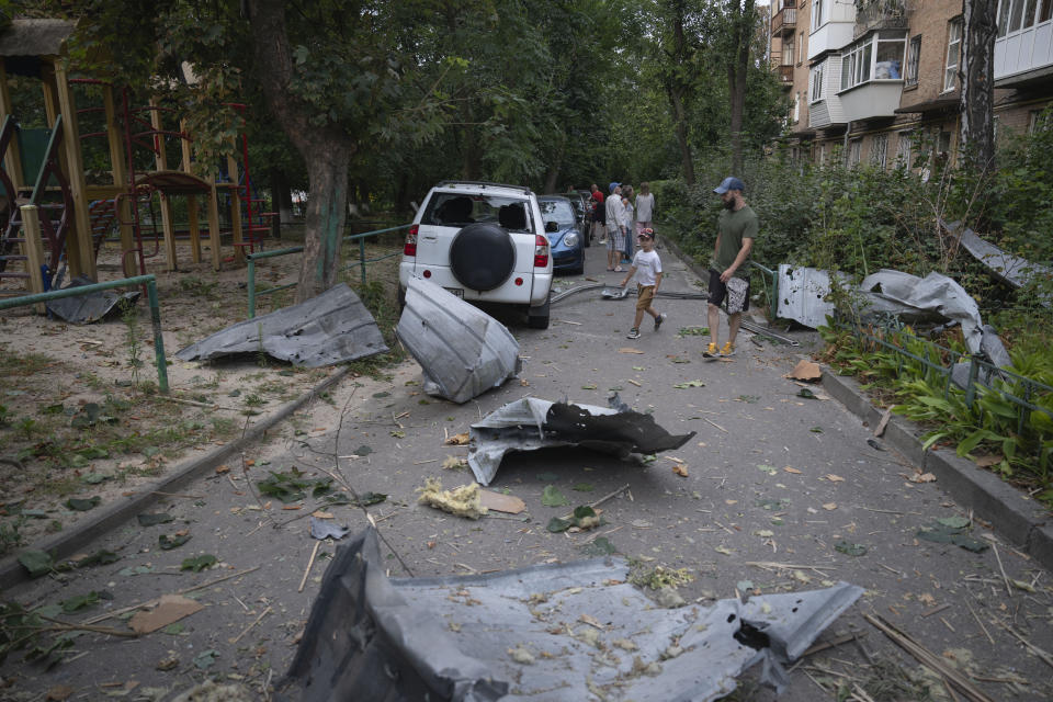 Local residents pass by debris in Kyiv, Ukraine, Wednesday, Aug. 30, 2023, that fell down from their damaged house after a Russian massive rocket attack . Over 20 rockets and drones have been shot down by the air defence system in Kyiv overnight. (AP Photo/Efrem Lukatsky)