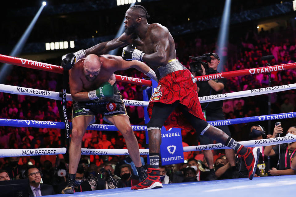 Deontay Wilder swings at Tyson Fury, of England, in a heavyweight championship boxing match Saturday, Oct. 9, 2021, in Las Vegas. (AP Photo/Chase Stevens)