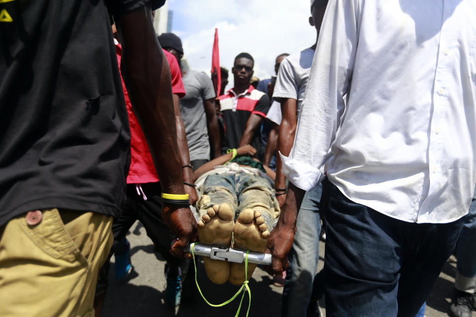 Protesters carry the body of man toward police, who they blame for his death, during an anti-government demonstration in Port-au-Prince, Haiti, Sunday, June 9, 2019. Protesters denouncing corruption paralyzed much of the capital as they demanded the removal of President Jovenel Moise. (AP Photo/Dieu Nalio Chery)