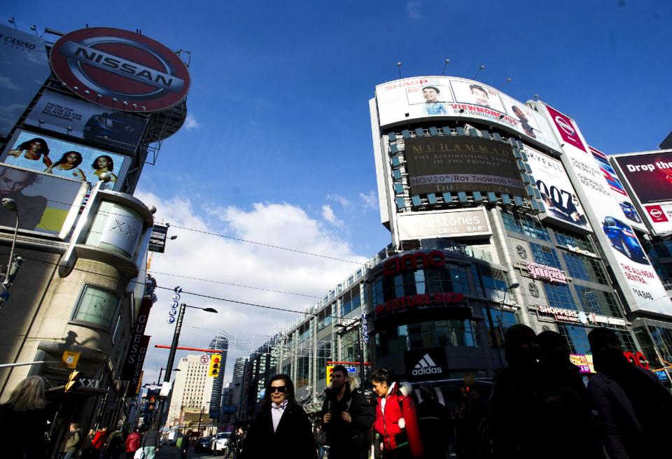 This Nov. 14, 2012 photo shows people crossing the street at Yonge and Dundas in the heart of downtown Toronto. The street moves up through the financial district to the Eaton Center, Toronto's largest downtown mall, and the Yonge-Dundas Square, a mini-Times Square where you can often catch free films, concerts, performances and festivals. (AP Photo/The Canadian Press, Nathan Denette)