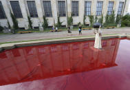 Visitors to the National Museum stop before a new statue of the late pope, St. John Paul II, throwing a stone at a "Poisoned Well", just hours before its official inauguration in the museum yard in Warsaw, Poland, Thursday, Sept. 24, 2020. The sculpture by Poland's Jerzy Kalina is said to be a response to a controversial 1999 sculpture by Italian Maurizio Cattelan in which the Polish-born pontiff was shown as being crushed by a similar stone. (AP Photo/Czarek Sokolowski)