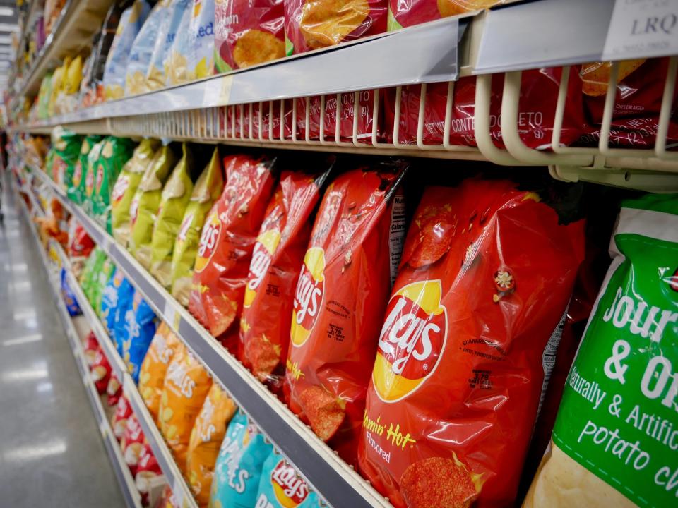 Grocery-store shelves with rows of multiple flavors of Lays potato chips