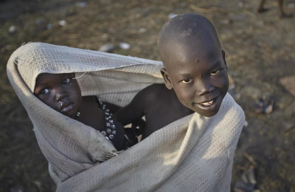 A displaced boy holds his young sister swaddled in a blanket, some of the thousands who fled the recent fighting between government and rebel forces in Bor by boat across the White Nile, in the town of Awerial, South Sudan Thursday, Jan. 2, 2014. The international Red Cross said Wednesday that the road from Bor to the nearby Awerial area "is lined with thousands of people" waiting for boats so they could cross the Nile River and that the gathering of displaced is "is the largest single identified concentration of displaced people in the country so far". (AP Photo/Ben Curtis)