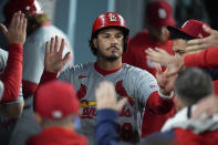 St. Louis Cardinals' Nolan Arenado, center, is greeted by teammates in the dugout after scoring on a single by Alec Burleson during the seventh inning of a baseball game against the Los Angeles Dodgers Saturday, March 30, 2024, in Los Angeles. (AP Photo/Jae C. Hong)