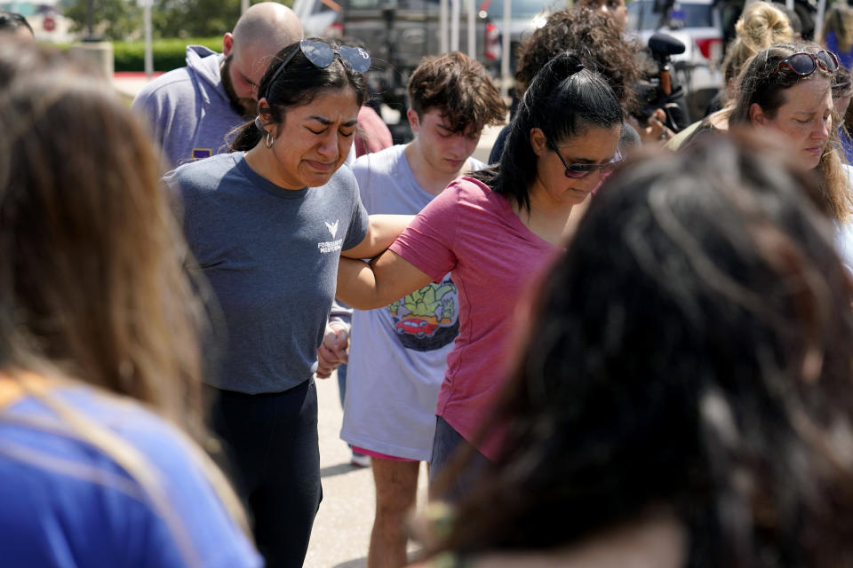 FILE - Veronica Rodriguez, left, of Dallas, reacts as she gathers in a circle with others in prayer by a makeshift memorial near the mall where several people were killed in Saturday's mass shooting, Monday, May 8, 2023, in Allen, Texas. A 33-year-old man with an arsenal of legally-purchased firearms killed eight people and wounded seven others at a Dallas-area shopping center. He had posted online about his white supremacist and misogynistic views. A police officer fatally shot him within four minutes. (AP Photo/Tony Gutierrez, File)