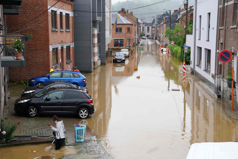 A woman stands in a flooded street in Rochefort on July 15 2021 as disaster plan has been declared in Belgium's provinces of Liege, Luxembourg and Namur after heavy rains and floods lashing western Europe have killed at least two people in the country. (Photo by ANTHONY DEHEZ / AFP)