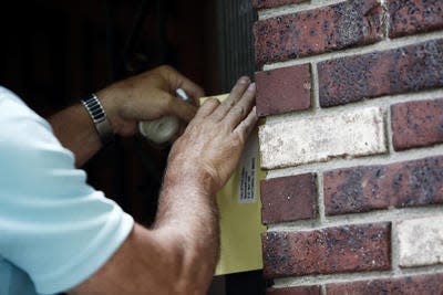 City code inspector Dale Wood issues citations for over-occupancy under the U+2 law at a home on Parklake Drive and Yucca Street in this 2014 file photo.