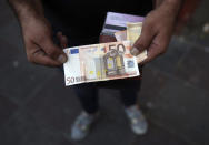 An Iranian street money exchanger holds a 50 euro banknote in downtown Tehran, Iran, Monday, July 30, 2018. Iran's currency has dropped to a record low ahead of the imposition of renewed American sanctions, with many fearing prolonged economic suffering or possible civil unrest. (AP Photo/Vahid Salemi)