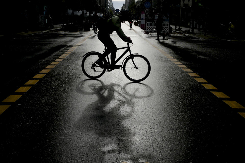 A man of a bike crosses the nearly deserted Fridrichstrasse one of Germany's capital main shopping streets, in Berlin, Germany, Monday, Nov. 2, 2020. New measures to stop the spread of the coronavirus come into force today in Germany. (AP Photo/Markus Schreiber)