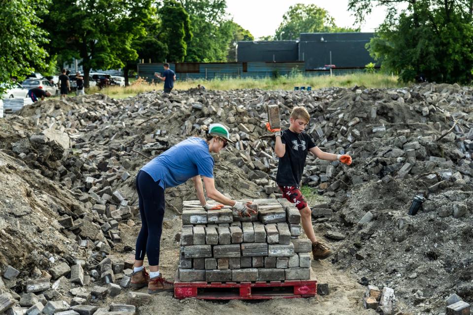 Erin Schwiezer, left, of Ferndale, and Ashton Wedge, of Detroit, work on stacking Nelsonville block pavers that are in good condition onto a pallet at a lot along East Vernor Highway in Detroit on Thursday, July 7, 2022. The pavers were donated from ITC and DTE to the city of Detroit to use for repairing Virginia Park Street in Detroit.