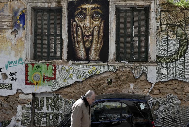 A man walks past a building adorned with graffitis and slogans reading 'Euro' in central Athens, Greece, on March 19, 2015