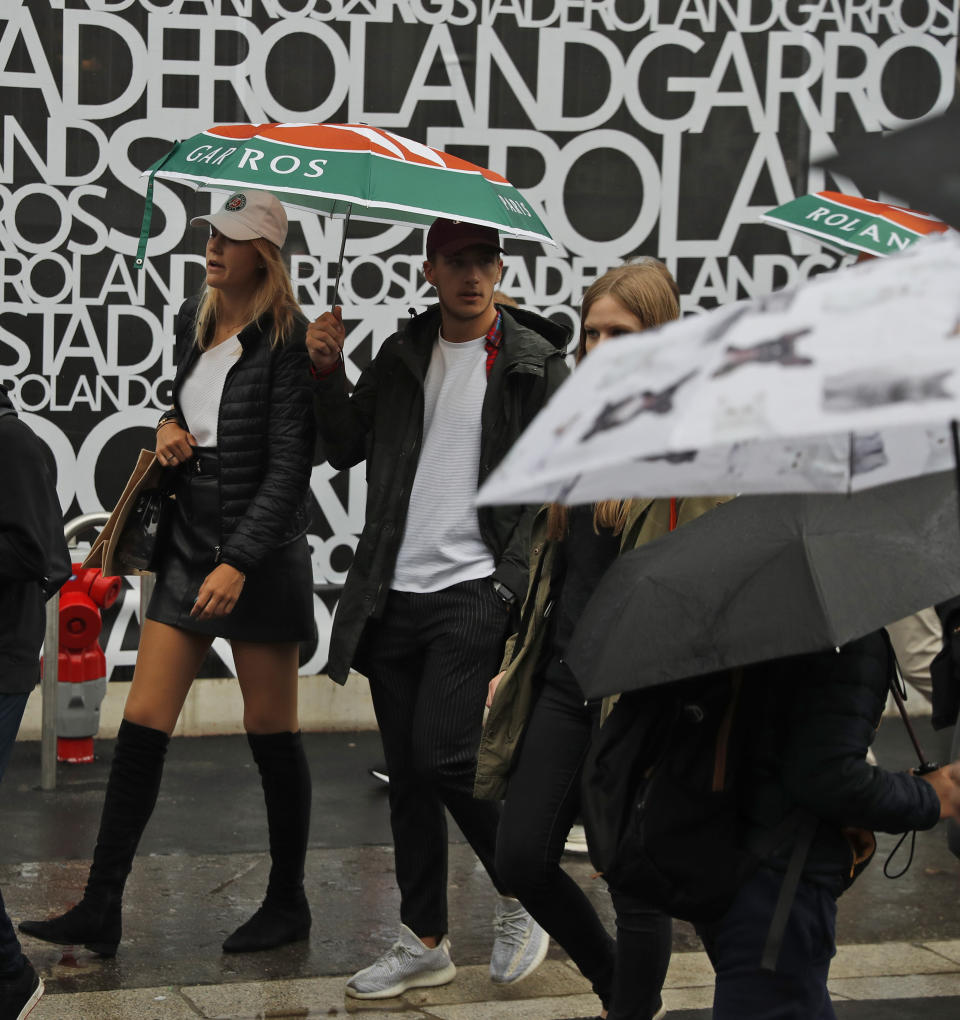 Spectators with umbrellas arrive for the quarterfinal matches of the French Open tennis tournament at the Roland Garros stadium in Paris, Wednesday, June 5, 2019. (AP Photo/Pavel Golovkin)