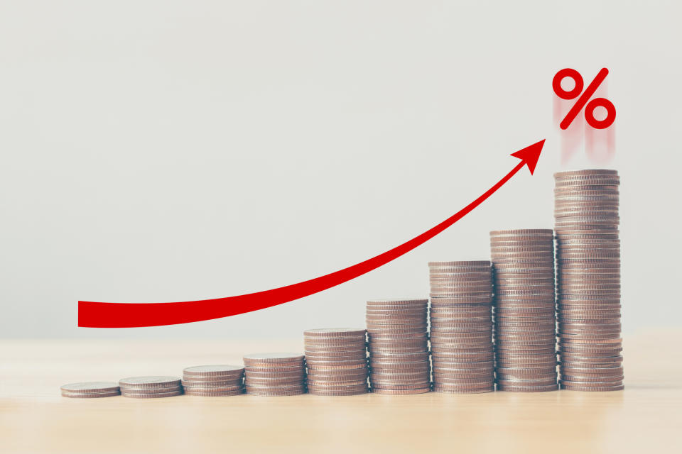 Rising stacks of coins with a red arrow pointing to a percent sign.