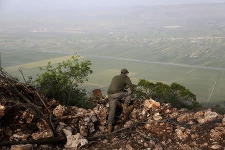 A rebel fighter stands on a hill overlooking al-Ghab plain, as he monitors the progress of the fighting from the Jabal al-Akrad area in Syria's northwestern Latakia province, April 29, 2015. REUTERS/Khalil Ashawi