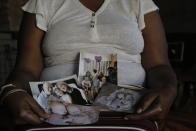 Mandy Sinanyoni, nanny of the three daughters of Graham and Lauren Dickason, holds photographs of the Dickason family in her Pretoria, South Africa home, Friday Sept. 17, 2021. Maya, Karla and Liane Dickason were found dead in the Timaru, New Zealand home they just move into from South Africa. A 40-year-old woman identified by police as Lauren Dickason was charged Friday with killing three young girls in a crime that has shocked New Zealand. (AP Photo/Sebabatso Mosamo)