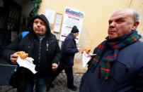 Needy people eat cheeseburgers donated by McDonald's to a charity organization which bestowed them at a walk-in clinic in Rome, Italy January 16, 2017. REUTERS/Tony Gentile