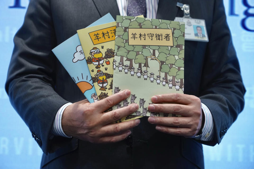 FILE - Li Kwai-wah, senior superintendent of Police National Security Department, poses with evidence including three children's books on stories that revolve around a village of sheep which has to deal with wolves from a different village, before a press conference in Hong Kong Thursday, July 22, 2021. Five Hong Kong speech therapists were convicted of sedition on Wednesday, Sept. 7, 2022, after they printed a series of children’s books about sheep and wolves that a court said was aimed at inciting hatred against authorities. (AP Photo/Vincent Yu, File)