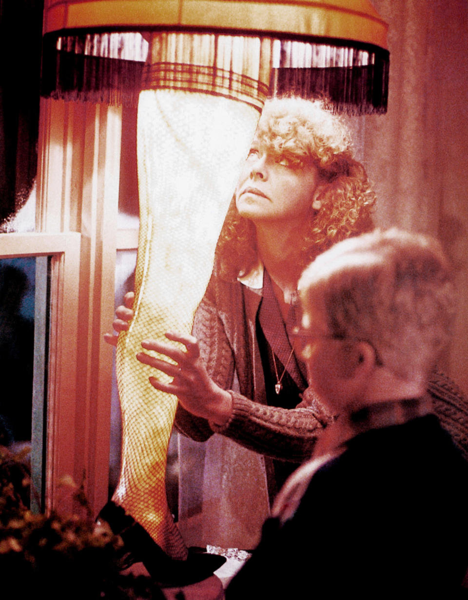 A woman and a child from "A Christmas Story" examine a lamp with a shade resembling a woman's leg