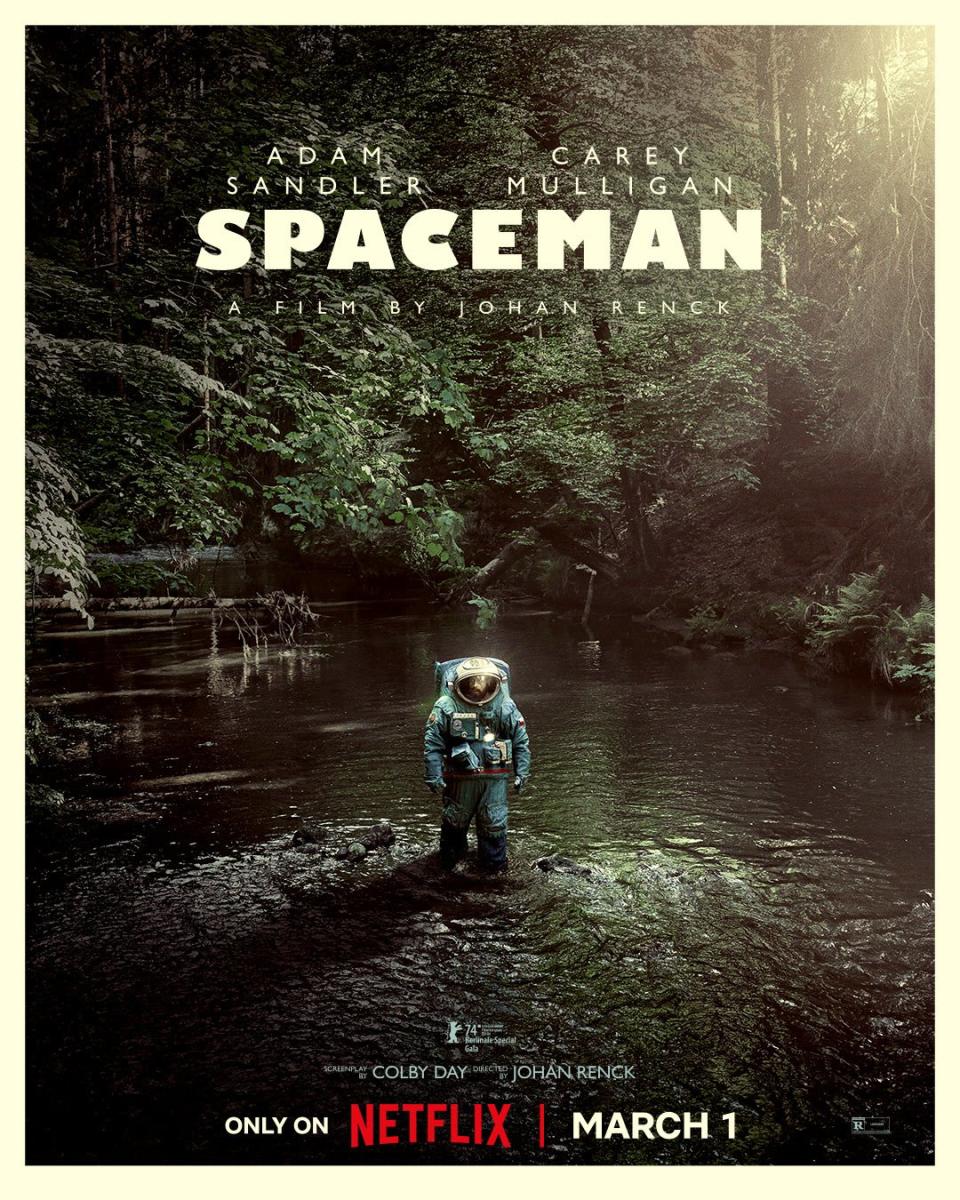 a person in a space suit stands in a stream in a wooded area