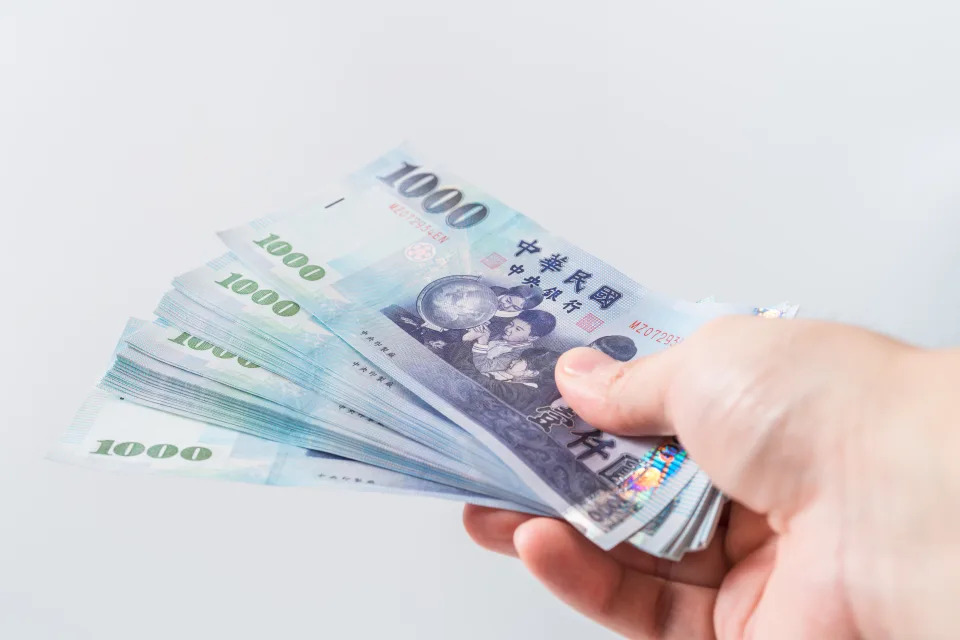 A hand holding a 1000 New Taiwan Dollar bill.