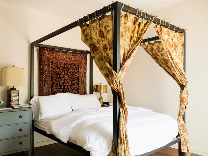 Bed with suspended metal frame and yellow floral sheets