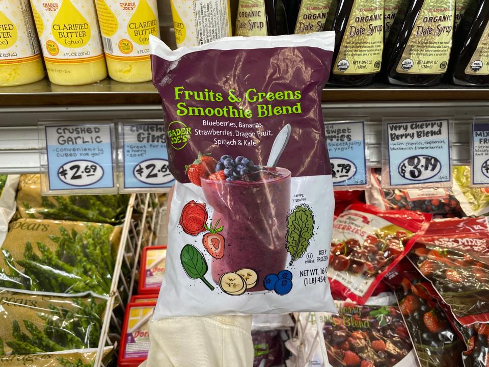 hand holding a bag of frozen smoothie blend in the freezer aisle at trader joes