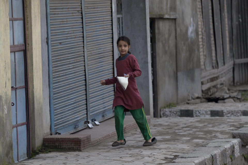 An Kashmiri girl rushes towards her home after buying milk during security lockdown in Srinagar, Indian controlled Kashmir, Sunday, Feb. 24, 2019. Shops and businesses have closed in Kashmir to protest a sweeping crackdown against activists seeking the end of Indian rule in the disputed region. (AP Photo/ Dar Yasin)