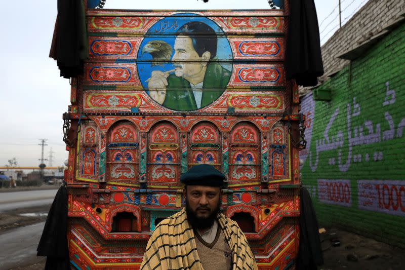 Muhammad Akram poses in front of his decorated supply truck, in Peshawar