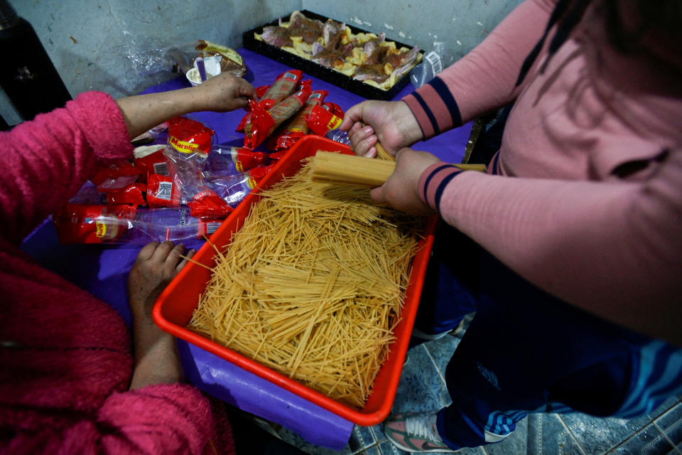 Voluntarios de un comedor de beneficencia sacan espaguetis de su envoltorio antes de cocinar un guiso que se servirá en raciones a las familias, en Villa Soldati, en las afueras de Buenos Aires, Argentina, el 10 de septiembre de 2024. REUTERS/Mariana Nedelcu/Foto de archivo