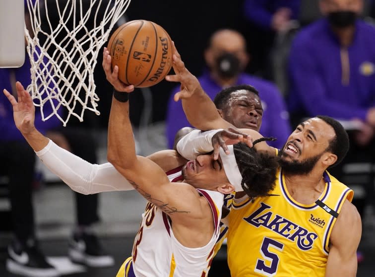 Cleveland Cavaliers guard Brodric Thomas, left, is fouled while shooting by Los Angeles Lakers guard Dennis Schroder, center, as guard Talen Horton-Tucker blocks during the second half of an NBA basketball game Friday, March 26, 2021, in Los Angeles. (AP Photo/Mark J. Terrill)