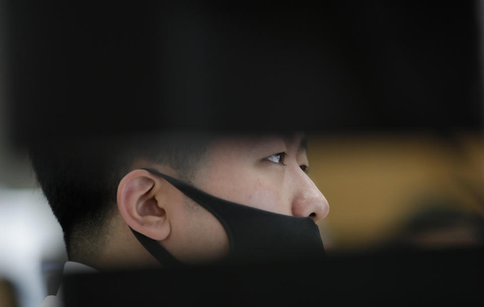 An employee of a bank wearing a face mask watches the computer monitors at the foreign exchange dealing room in Seoul, South Korea, Tuesday, March 31, 2020. Asian shares surged Tuesday after a rally in U.S. stocks, mostly spurred by health care companies' announcements of developments that could aid in the coronavirus outbreak. (AP Photo/Lee Jin-man)