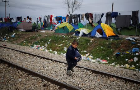 A migrant boy walks along railway tracks at a makeshift camp on the Greek-Macedonian border near the village of Idomeni, Greece March 10, 2016. REUTERS/Stoyan Nenov