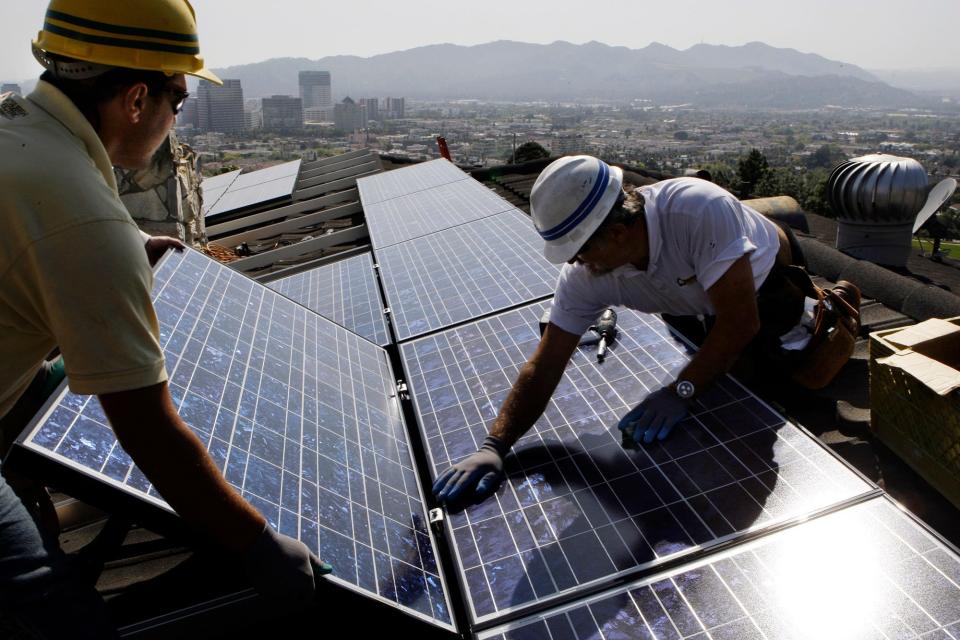 In this March 23, 2010, file photo, team leader Edward Boghosian, right, and electrician Patrick Aziz, both employees of California Green Design, install solar electrical panels on the roof of a home in Glendale, Calif. California has set a goal of getting 33% of its electricity from renewables by 2020 and has a separate effort to install nearly 2,000 megawatts worth of solar panels on rooftops by the end of 2016.