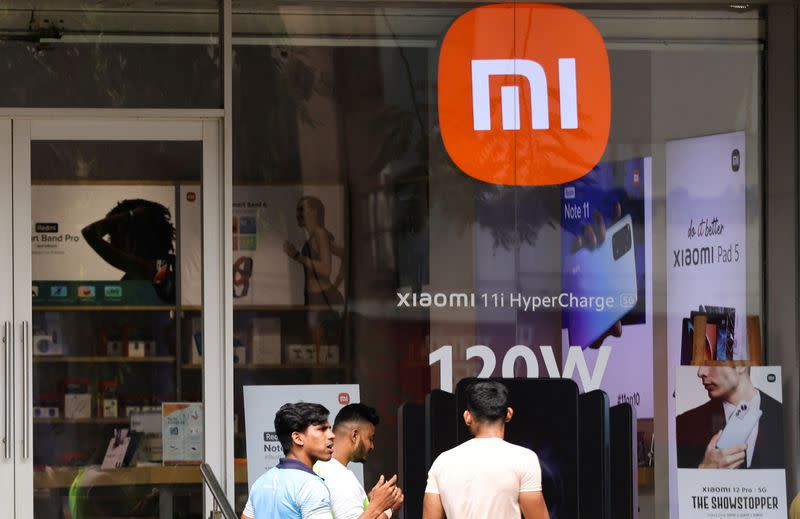 FILE PHOTO: People walk past Xiaomi, a Chinese manufacturer of consumer electronics, store in Mumbai