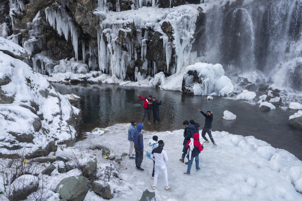Tourists visit a partially frozen waterfall in Drang village, northwest of Srinagar, Indian controlled Kashmir Thursday, Dec. 21, 2023. This is the time of "Chillai Kalan," also called "The Great Winter," a Kashmiri phrase which defines the harshest 40 days of cold in disputed Kashmir that commence in late December and extend into January and early February. Renowned for its breathtaking landscapes, Kashmir in winter transforms into a wonderland. Tourists fill its hotels to ski, sledge and trek the Himalayan landscape.(AP Photo/Dar Yasin)