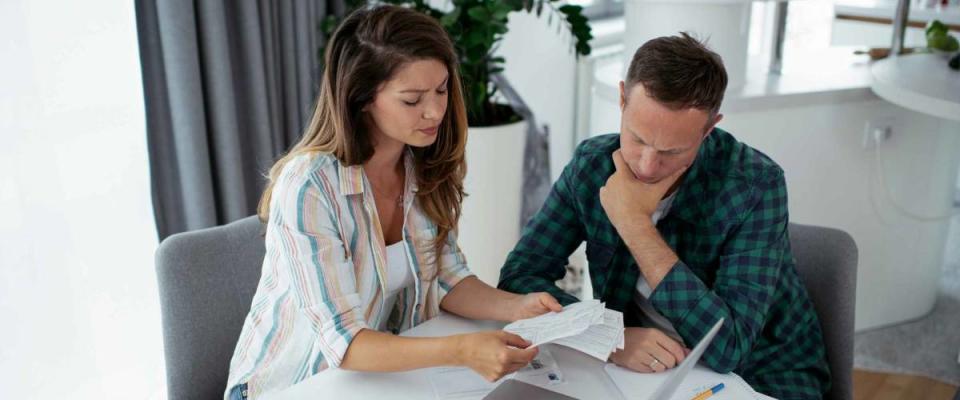 Husband and wife preparing bills to pay sitting at kitchen table.