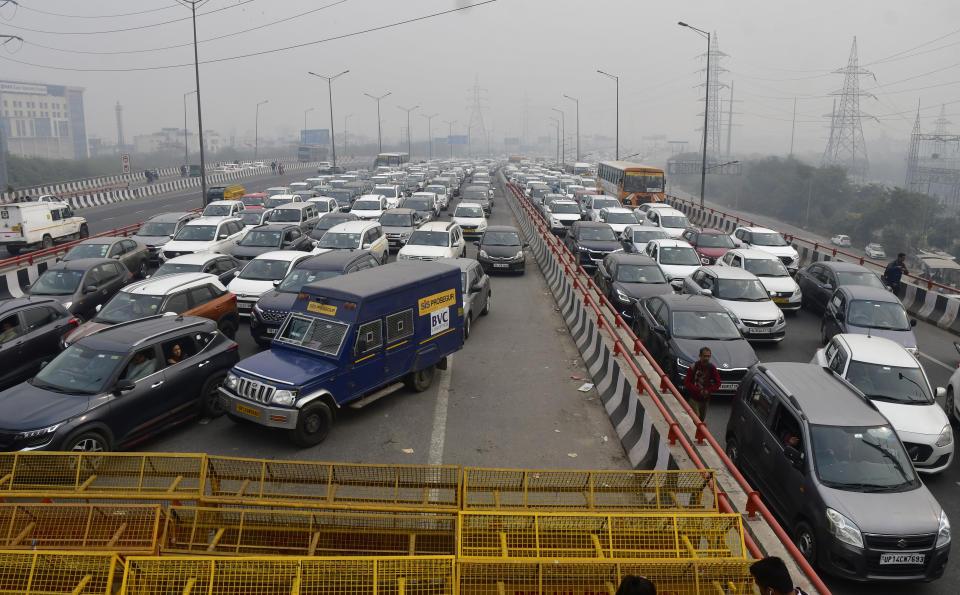 Vehciles move at snail pace after police barricade a major highway at Ghazipur near New Delhi to stop thousands of protesting farmers from entering the capital, India, Tuesday, Feb.13, 2024. (AP Photo)