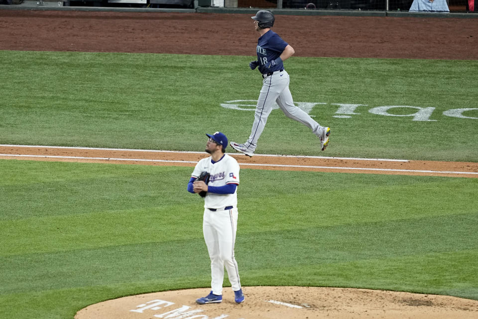 Seattle Mariners' Mitch Garver jogs to first after earning a walk off of Texas Rangers starting pitcher Dane Dunning, foreground, during the fourth inning of a baseball game in Arlington, Texas, Tuesday, April 23, 2024. (AP Photo/Tony Gutierrez)