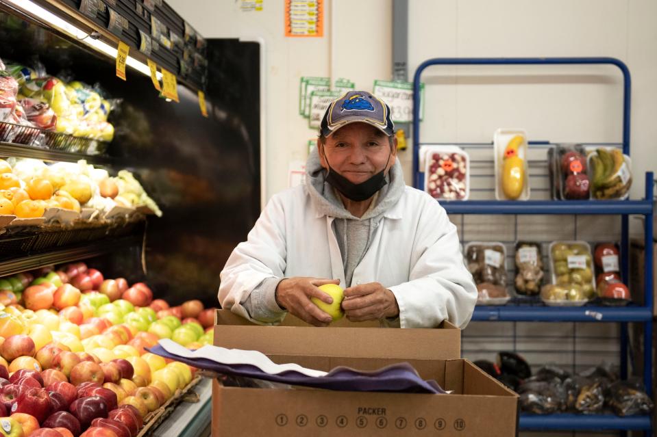 A staff member stacks apples to shelves at Selecto Supermarket in Bristol on Monday, Nov. 7, 2022.