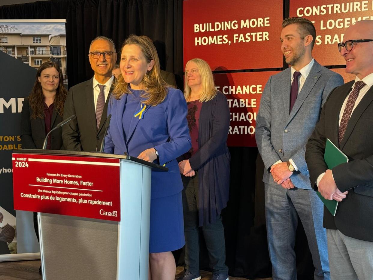Deputy Prime Minister and Finance Minister Chrystia Freeland, at the lectern, announced new and expanded federal programs to stimulate construction of rental housing on Wednesday. Freeland made the announcement at a Home Ed affordable apartment complex in Edmonton, alongside Edmonton Mayor Amarjeet Sohi, who is left of Freeland. (Janet French/CBC - image credit)