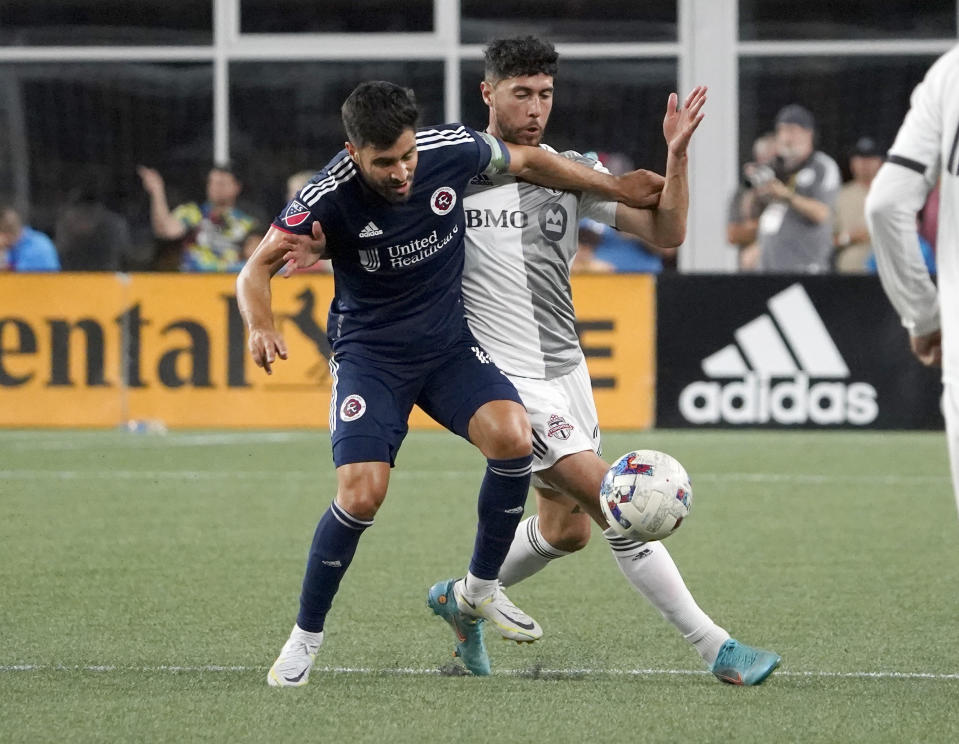 New England Revolution's Carles Gil, left, and Toronto FC's Jonathan Osorio vie for the ball during the first half of an MLS soccer match Saturday, July 30, 2022, in Foxborough, Mass. (AP Photo/Mary Schwalm)